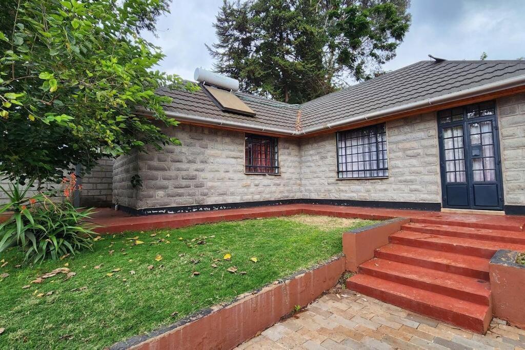 a house with a yard with stairs and a house at Ace House in Nyeri