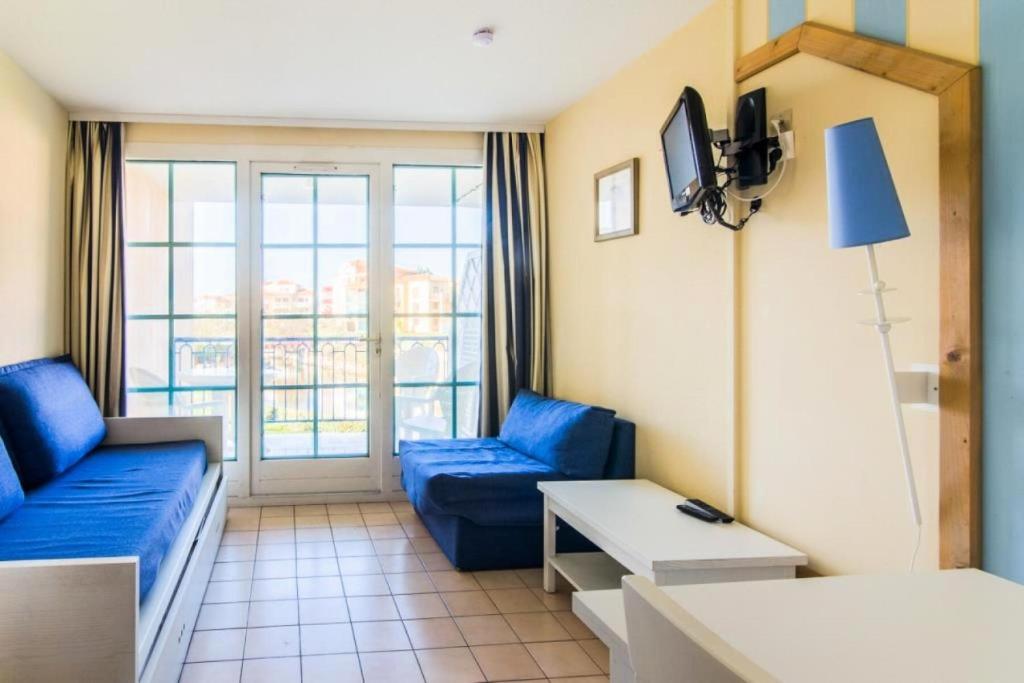 un salon avec un canapé bleu et une télévision dans l'établissement Résidence Port Bourgenay - maeva Home - Studio 5 Personnes Sélection MAE-2311, à Talmont-Saint-Hilaire
