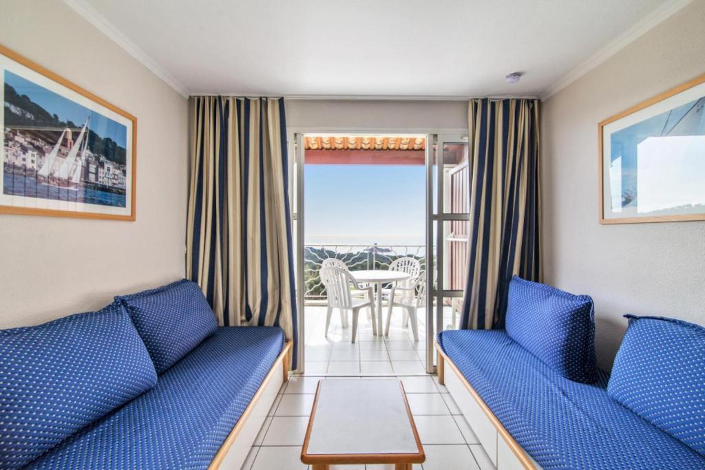 un salon avec deux canapés bleus et un balcon dans l'établissement Résidence le Hameau de Cap Esterel - maeva Home - Studio 5 Personnes - Confort MAE-2361, à Saint-Raphaël