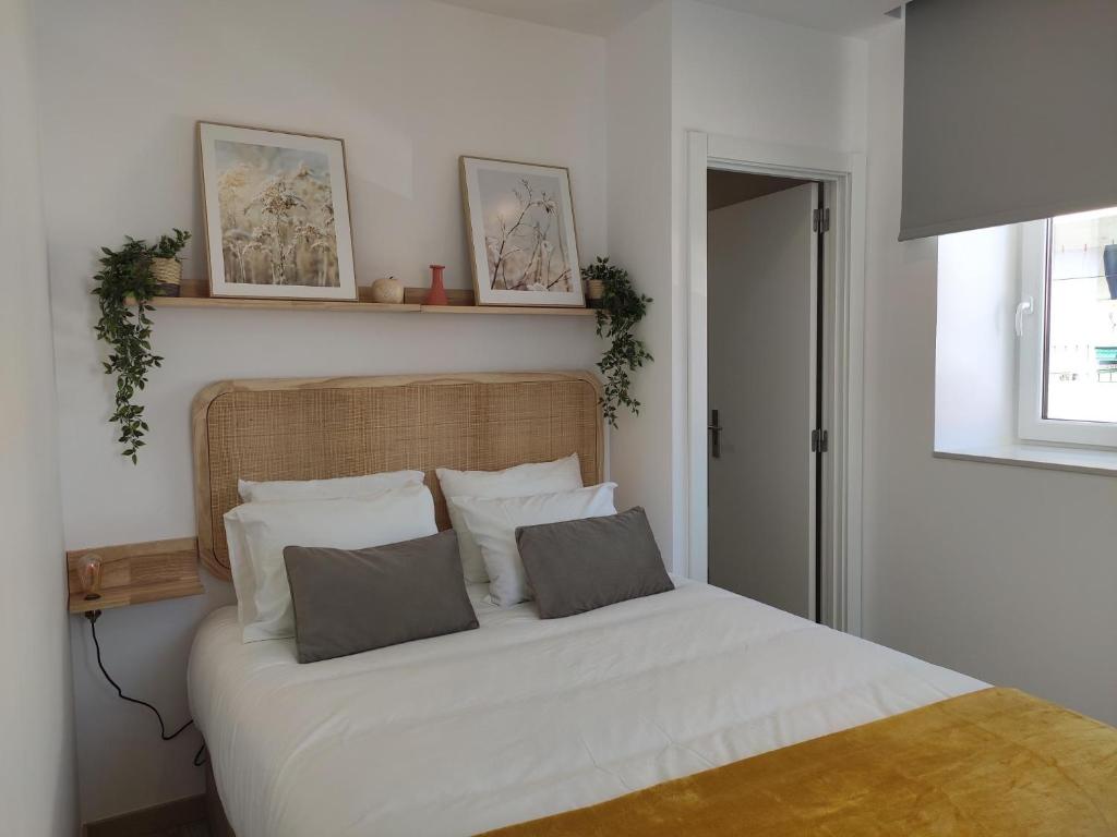 um quarto com uma cama com lençóis brancos e almofadas em Aveiro Ria House em Aveiro