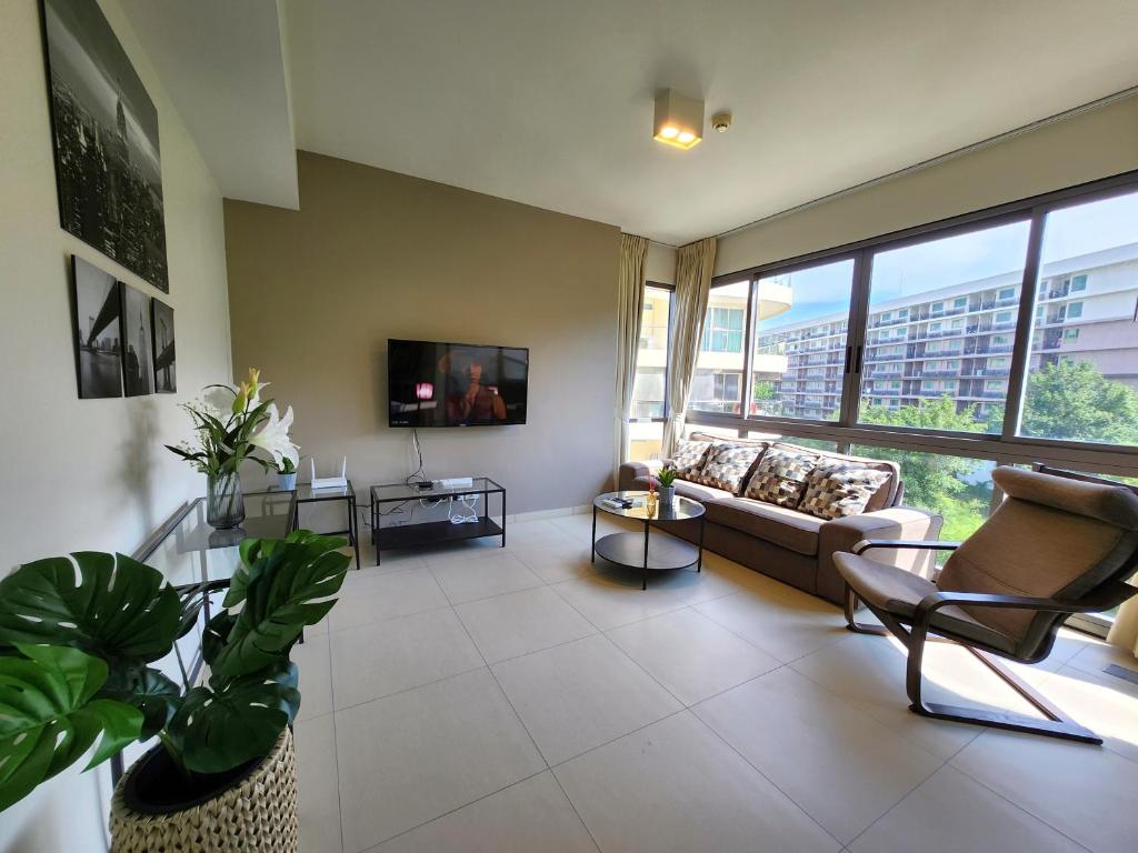 ein Wohnzimmer mit Sofa und Fernseher in der Unterkunft UNIXX Oasis : Grandeur 2BR Suite in Pattaya South