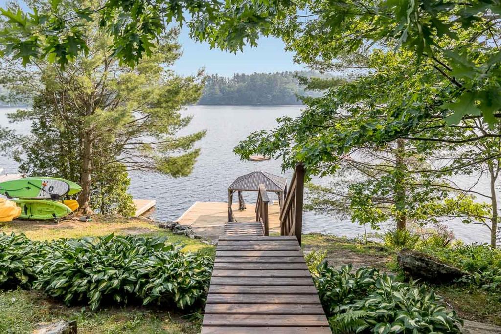 un camino de madera que conduce a un muelle en un lago en Muskoka Lakeshore Cottage Bliss, en Gravenhurst