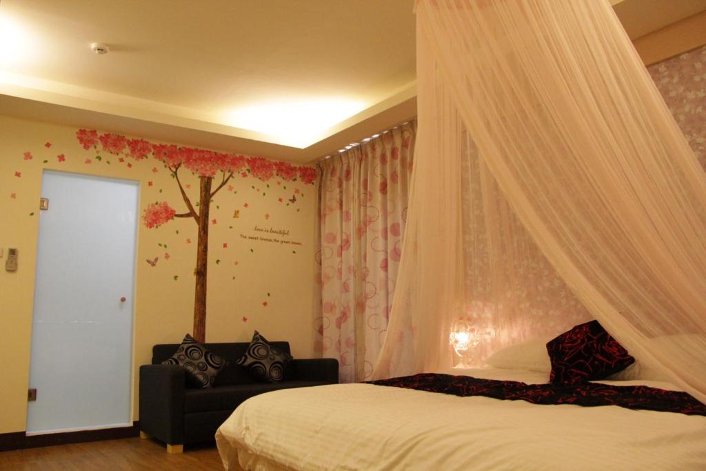 a bedroom with a canopy bed with a tree on the wall at Yilan Golf B&B in Wujie
