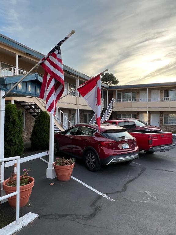 un coche rojo estacionado en un estacionamiento con banderas en Marco Polo Motel en Seattle