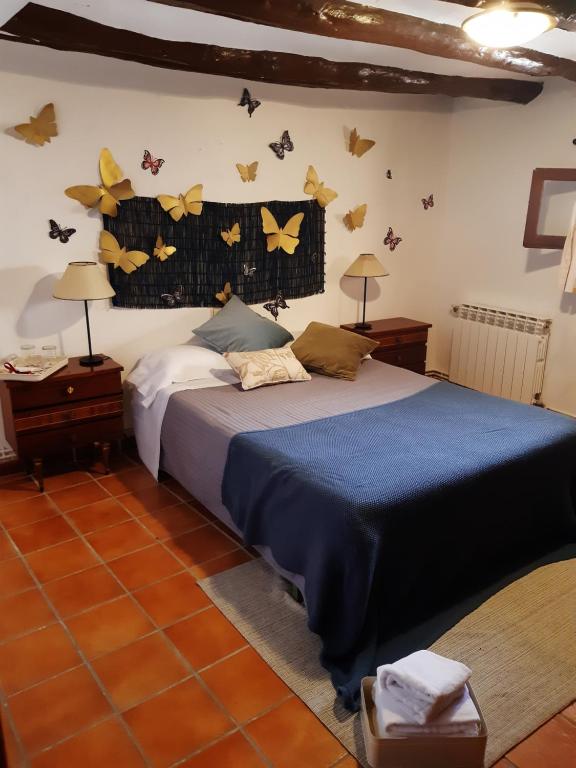 1 dormitorio con 1 cama con mariposas en la pared en Musas Gastro Casa Rural, en Valdealgorfa