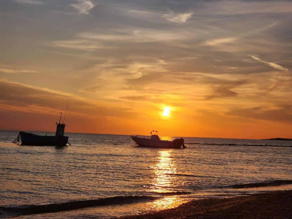 zwei Boote sitzen bei Sonnenuntergang im Meer in der Unterkunft A due passi dalle bellezze della Puglia in Sava
