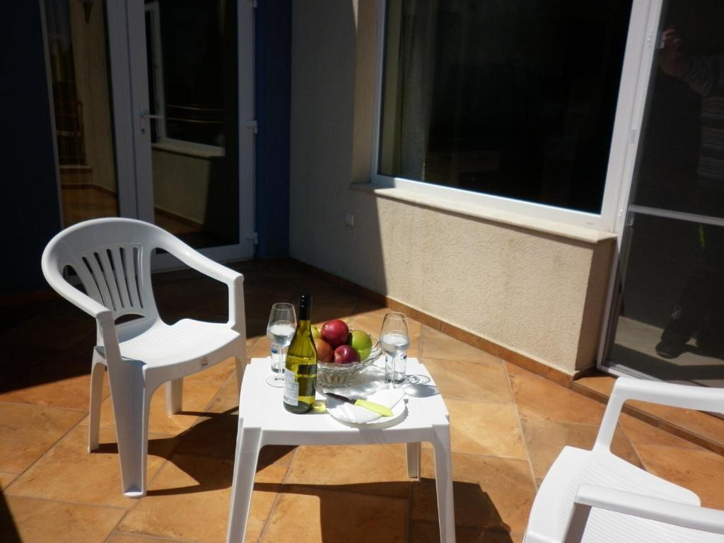 a table and chairs with a bowl of fruit and wine glasses at Hotel Marant in Sozopol