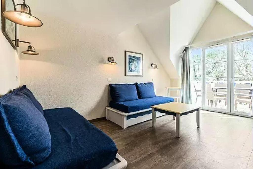 a living room with a blue couch and a table at Résidence Cap Azur - maeva Home - Appartement 3 Pièces 7 Personnes - Sélection MAE-5087 in Fouesnant