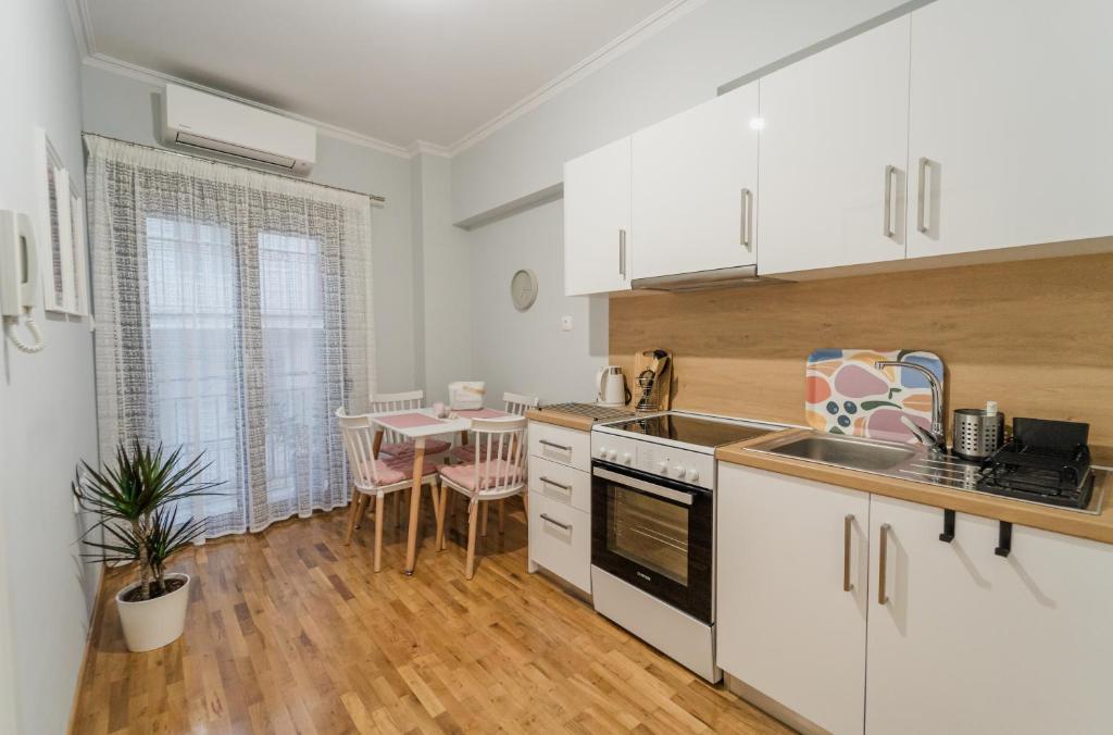 a kitchen with white cabinets and a table and a dining room at The Little Pigeon - Pink in Ioannina