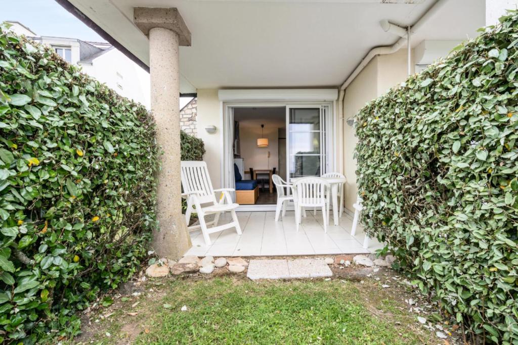- une terrasse couverte avec 2 chaises et un mur recouvert de lierre dans l'établissement Résidence Port du Crouesty - maeva Home - Studio 5 personnes - Confort - vue mer MAE-2887, à Arzon