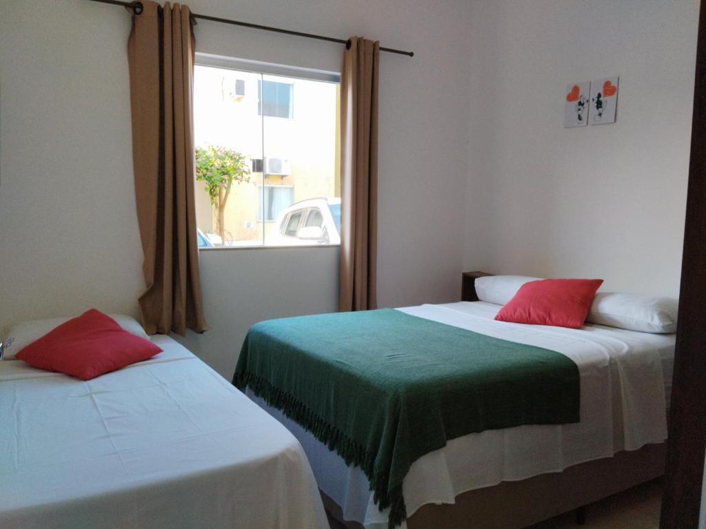 dwa łóżka w pokoju z oknem w obiekcie Apto Aconchegante na Praia Coroa Vermelha w mieście Santa Cruz Cabrália