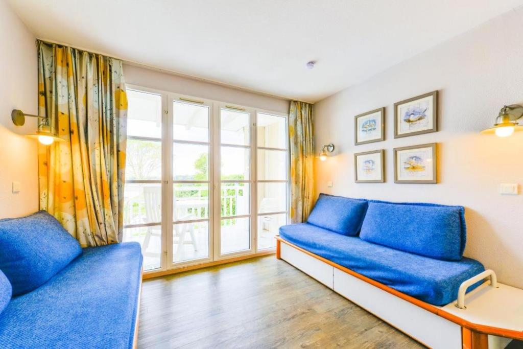 ein Wohnzimmer mit blauen Sofas und einem großen Fenster in der Unterkunft Le Cap Glénan - maeva Home - 2 Pièces 5 Personnes Confort MAE-5640 in Bénodet