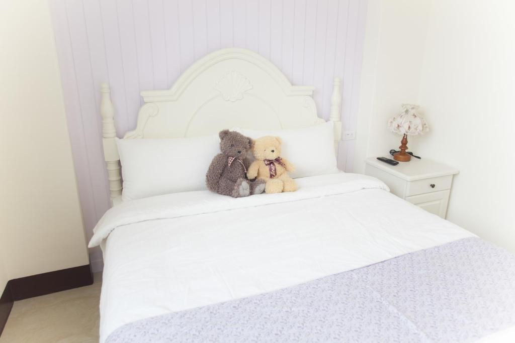 two teddy bears sitting on top of a white bed at Blue Cotton Candy B&amp;B in Taitung City
