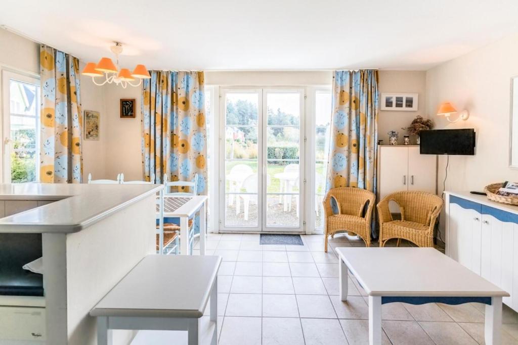 eine Küche und ein Esszimmer mit Tischen und Stühlen in der Unterkunft Les Maisons de Belle Dune - maeva Home - Maison 3 Pièces 6 Personnes Confort MAE-2273 in Fort-Mahon-Plage
