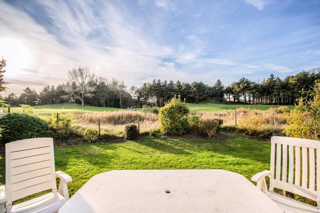 2 chaises blanches et une table dans la cour dans l'établissement Les Maisons de Belle Dune - maeva Home - Maison 3 Pièces 6 Personnes Confort MAE-2274, à Fort-Mahon-Plage