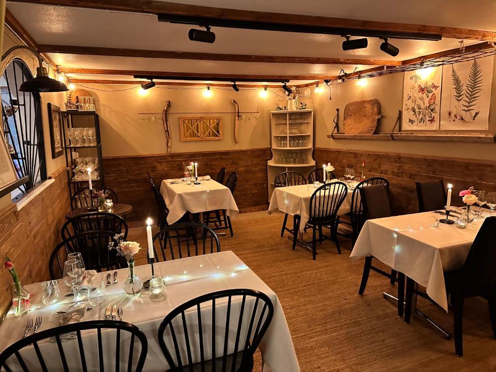 un restaurante con mesas blancas, sillas y luces en Boutiquehotell Dahlbogården, en Alingsås