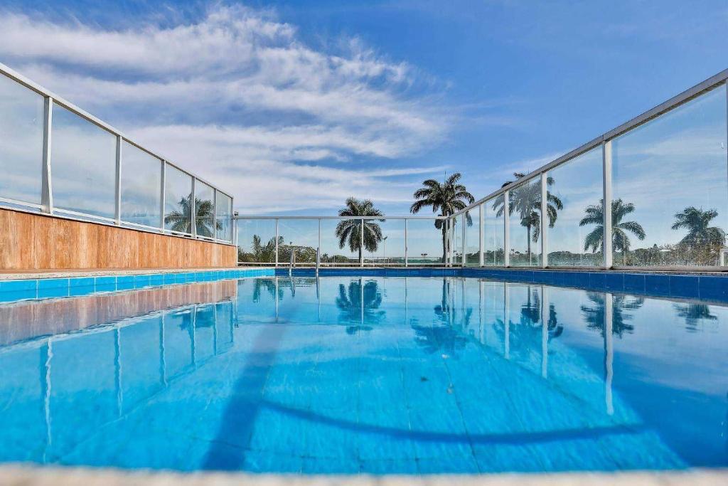 uma piscina com água azul e palmeiras em Hotel San Diego Pampulha - Flats Particular em Belo Horizonte