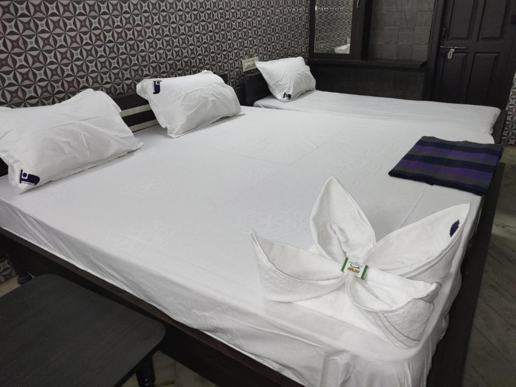 2 letti con lenzuola bianche e un tovagliolo sopra di Hotel Karthikeya Residency a Kākināda