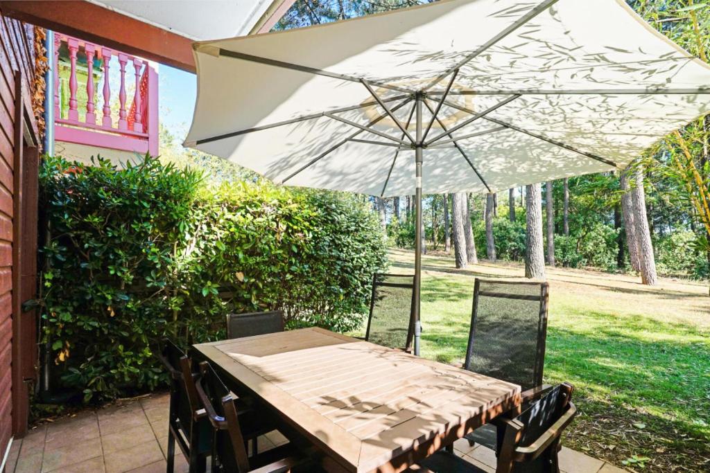 - une table avec un parasol sur la terrasse dans l'établissement Résidence Lacanau Les Pins - maeva Home - Maison 3 pièces 6 personnes Sélection MAE-9122, à Lacanau