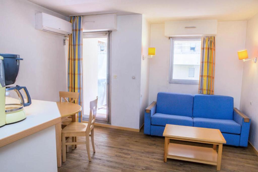 un salon avec un canapé bleu et une table dans l'établissement Résidence Promenade des Bains - maeva Home - Studio 4 Personnes Confort MAE-2296, à Saint-Raphaël