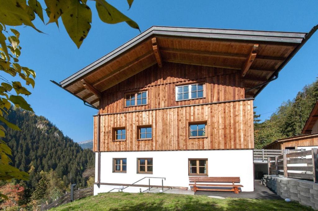 a house with a wooden roof and a bench at Rustic Farm in Tyrol with Mountain Views in Tobadill