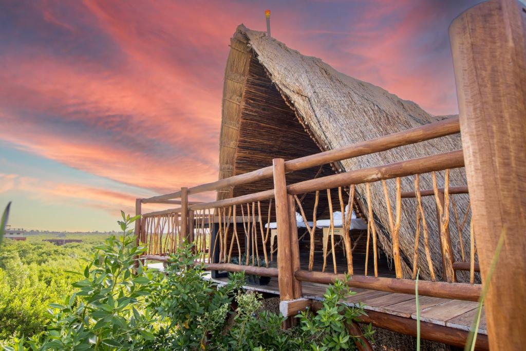 a building with a thatched roof with a sunset at Hotel Casa HX - Adults Only in Holbox Island