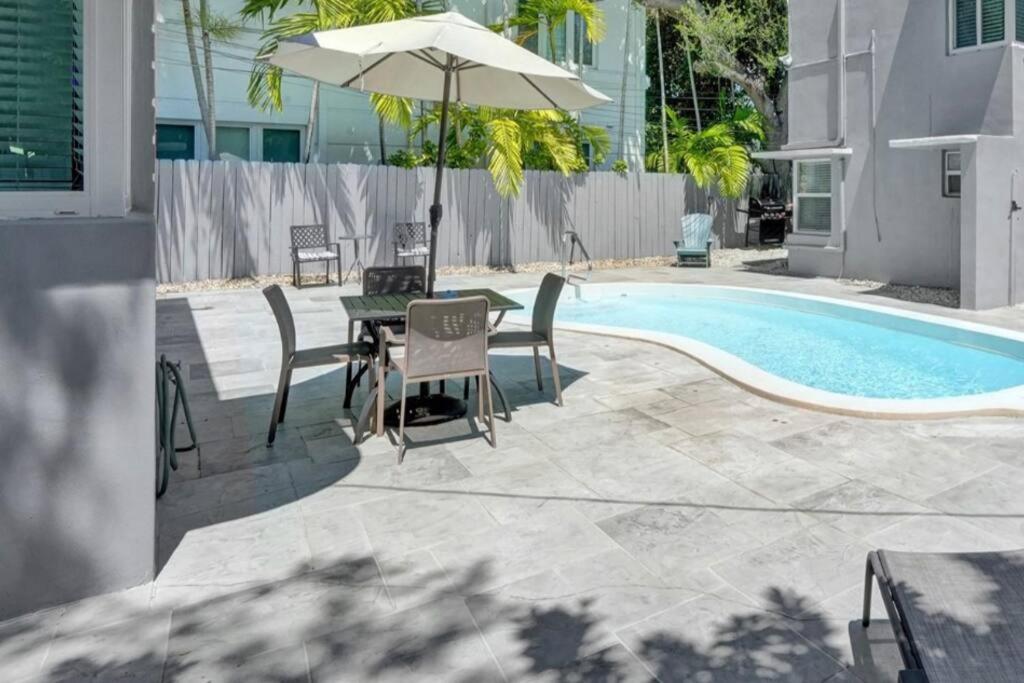 una mesa con sillas y una sombrilla junto a la piscina en Central & Stylish Oasis Slps 2, en Fort Lauderdale