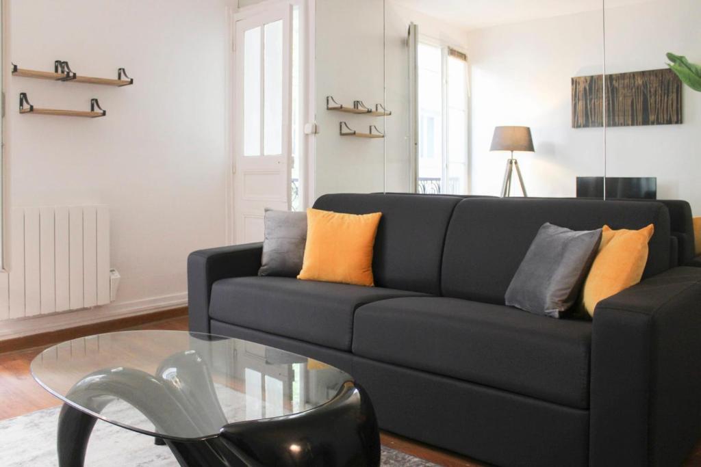 - un salon avec un canapé noir et une table en verre dans l'établissement Pretty love nest close to Père-Lachaise, à Paris