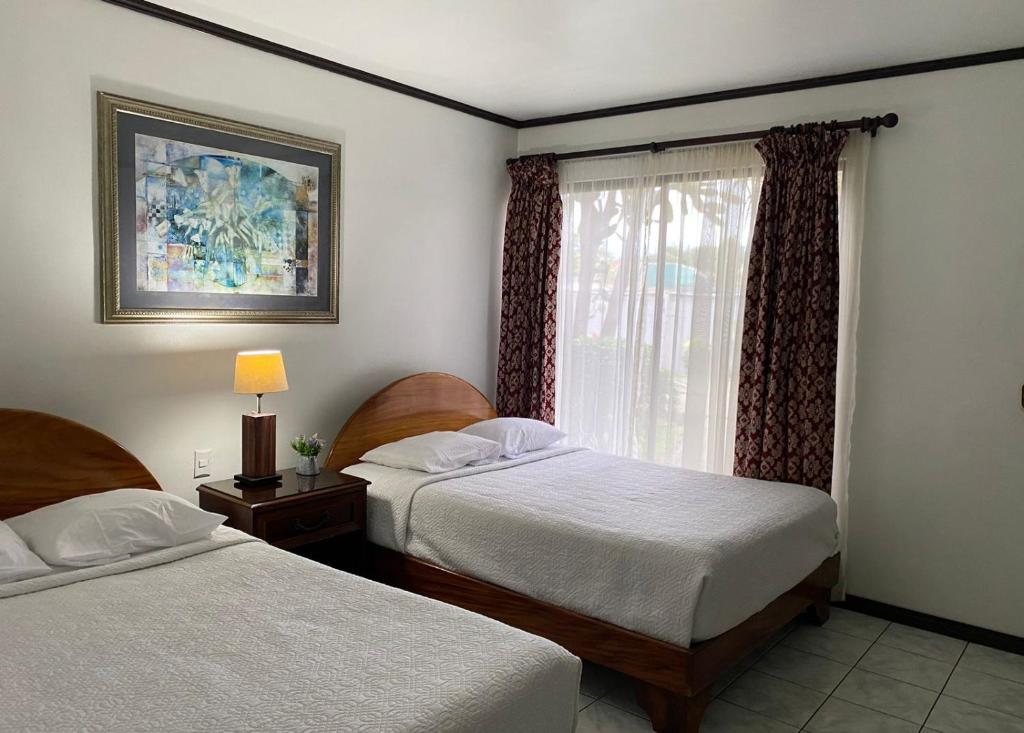 a bedroom with two beds and a window at Brillasol Airport Hotel in Alajuela