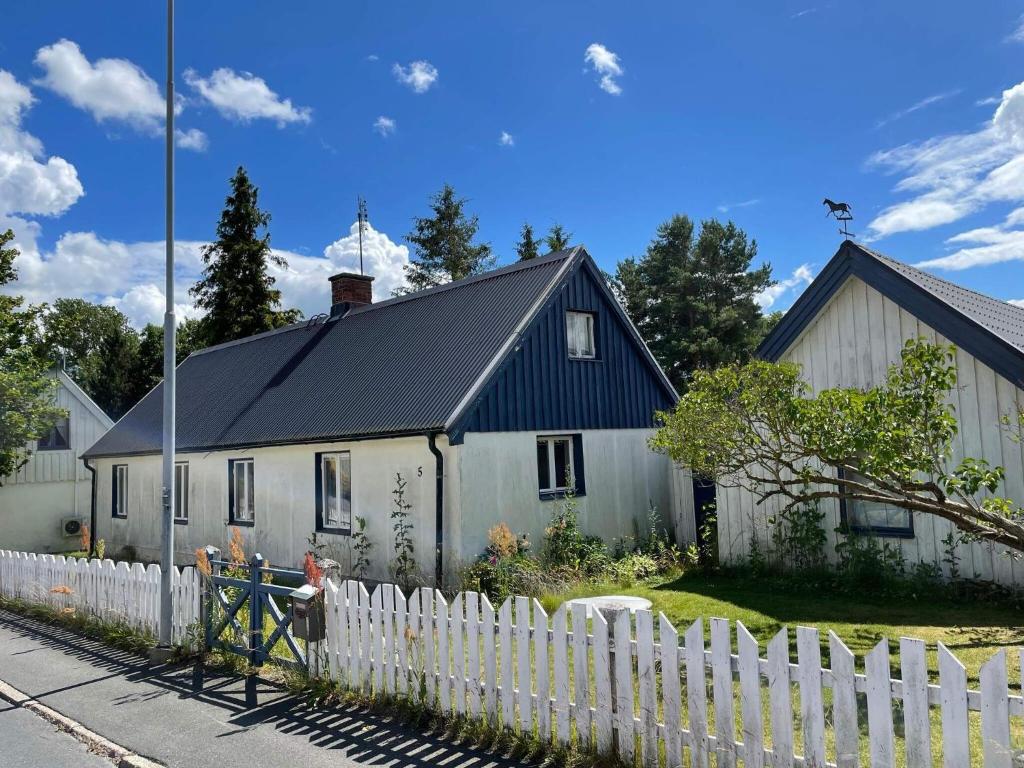 a white house with a black roof behind a white fence at Holiday home EVERÖD in Everöd