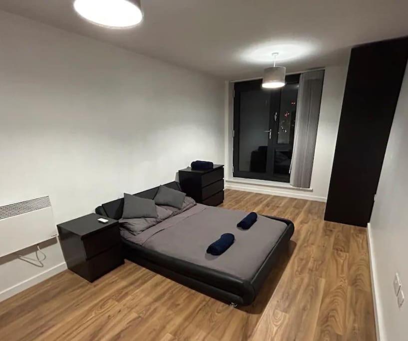 a bedroom with a bed and a large window at 2 bed apartment close to station with parking in London