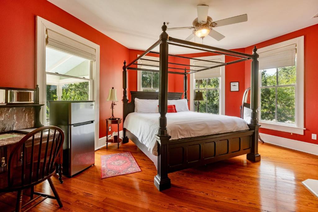um quarto com paredes cor de laranja e uma cama de dossel em Anticipation Room in Camellia Rose Inn Downtown em Gainesville