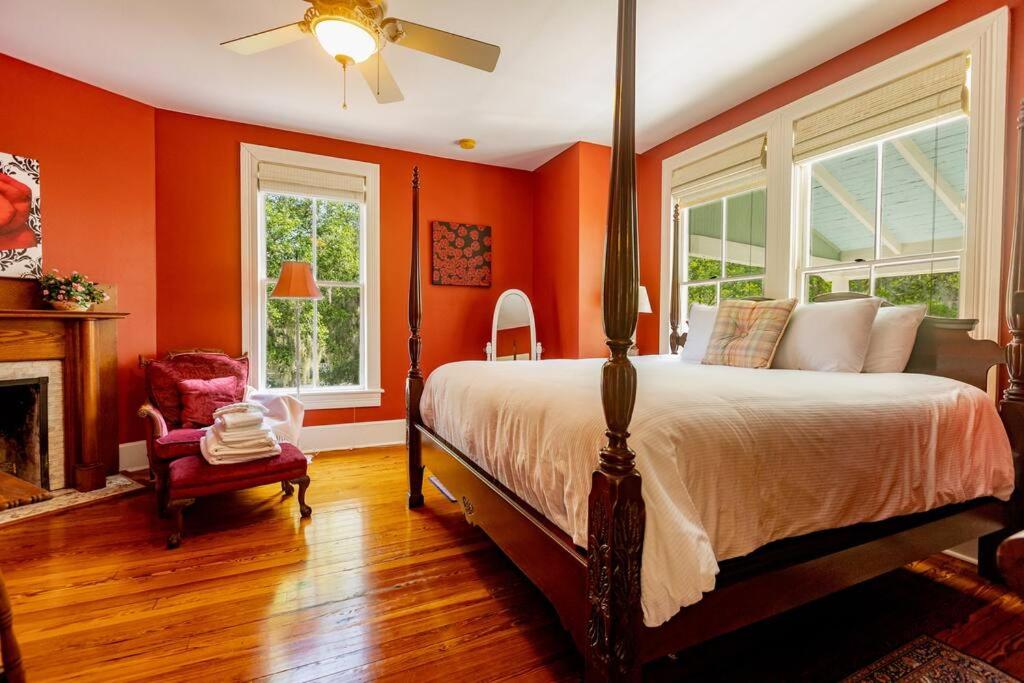 1 dormitorio con paredes de color naranja, 1 cama y chimenea en Briar Rose Room at Camellia Rose Inn Downtown, en Gainesville