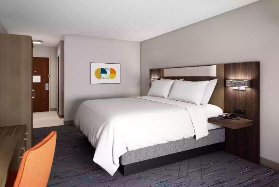 - une chambre avec un grand lit blanc et des chaises orange dans l'établissement Holiday Inn Express Jesup, an IHG Hotel, à Jesup