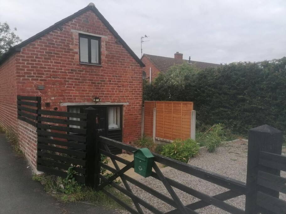 The Old Barn, Cosy Townhouse in Leominster في ليومنستر: منزل من الطوب الأحمر أمامه سور