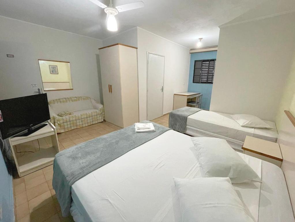 a hotel room with two beds and a flat screen tv at Central Park Hotel Residence in São Carlos