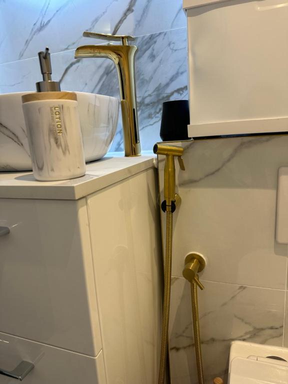 a bathroom with a sink and a gold faucet at Sweet home in Bagnolet