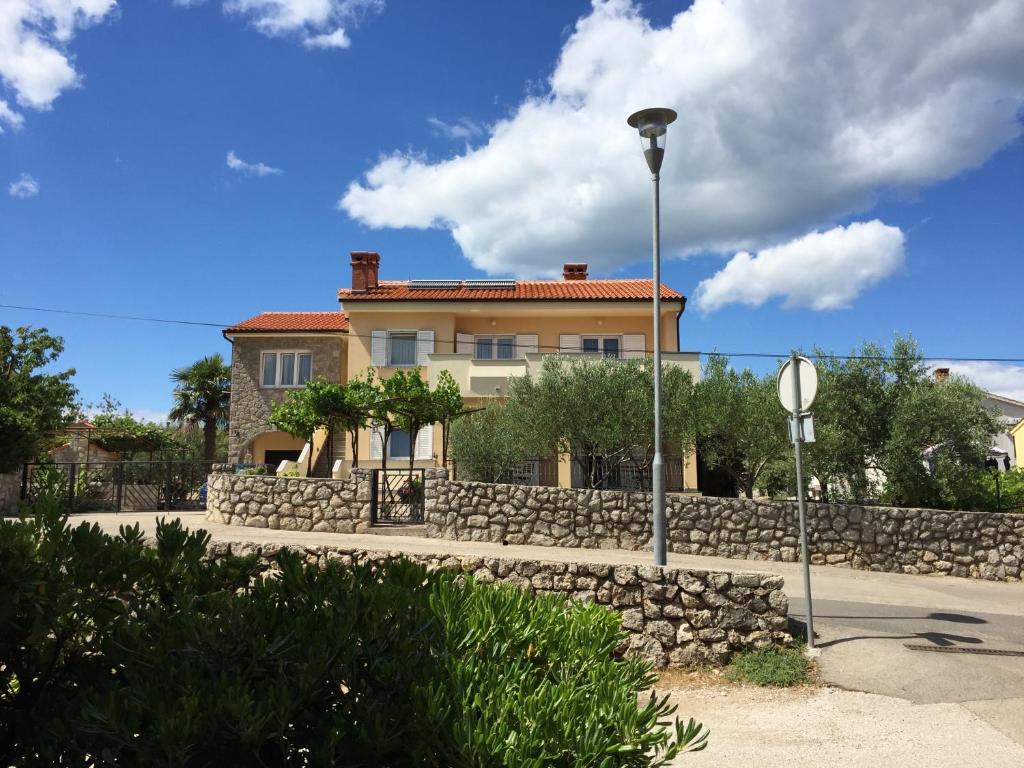 a house with a stone wall and a street light at Apartments Sanbrandin in Krk
