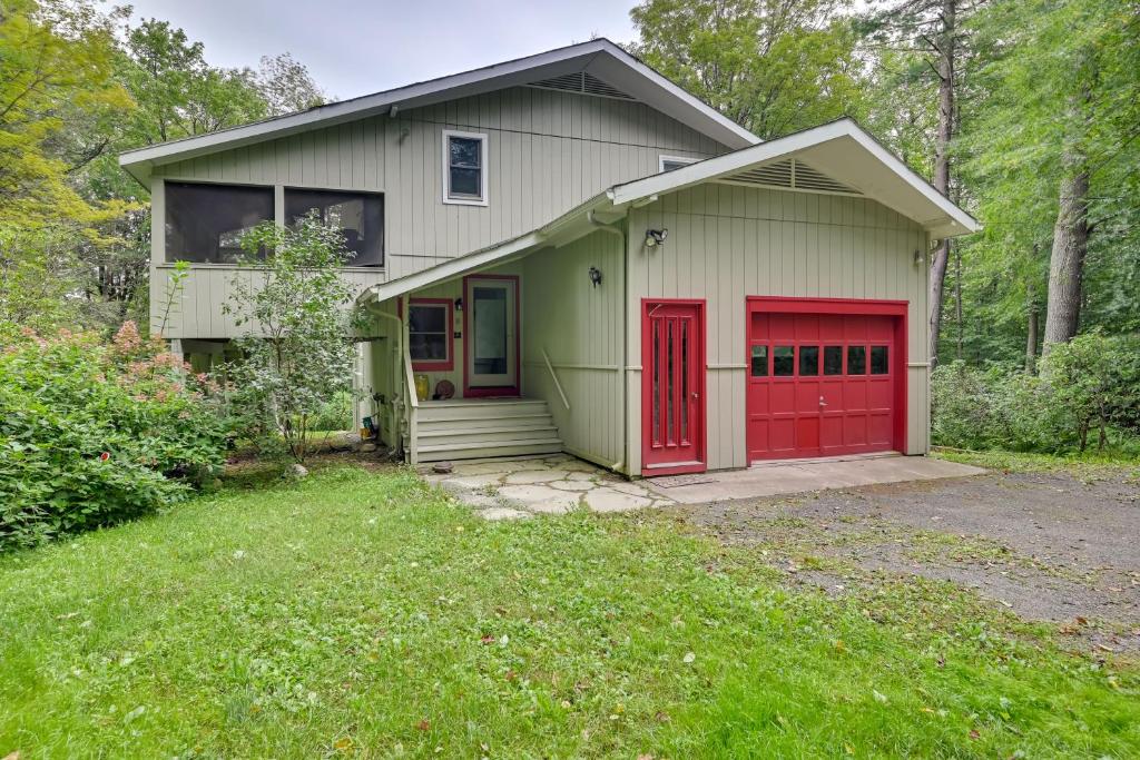 una pequeña casa con puertas rojas y un patio en Spacious Tolland Home with Deck and Screened Porch! en Sandisfield