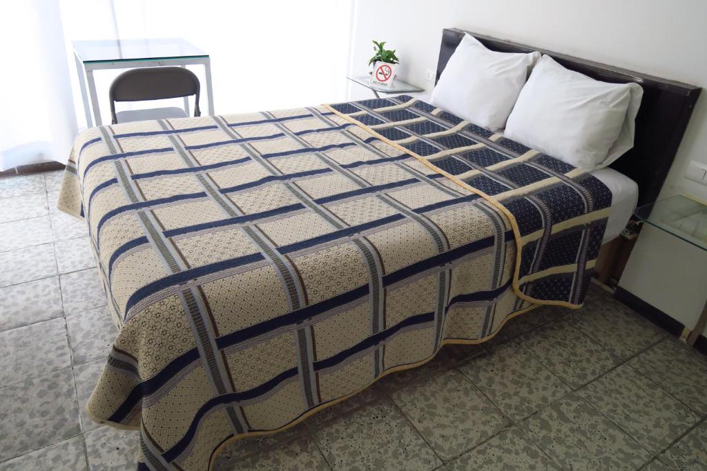 HOTEL LLANITO AGS في اغواسكالينتيس: سرير مع بطانيه وكرسي في الغرفه