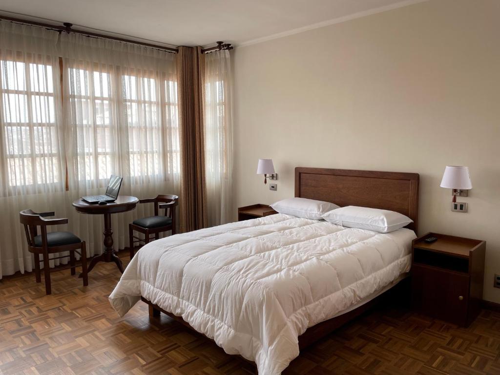 a bedroom with a bed and a table with a laptop at HOSPEDAJE SARABIA in Sucre
