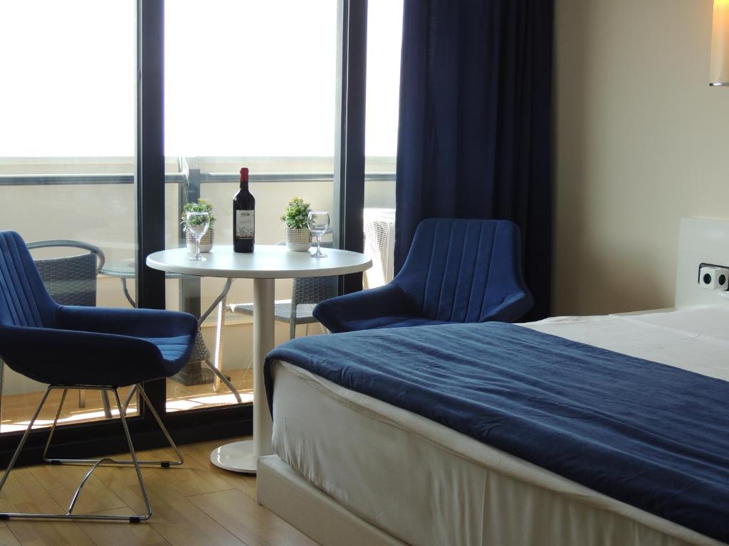 Un dormitorio con una cama y una mesa con una botella de vino en Orbi City Superhost, en Batumi
