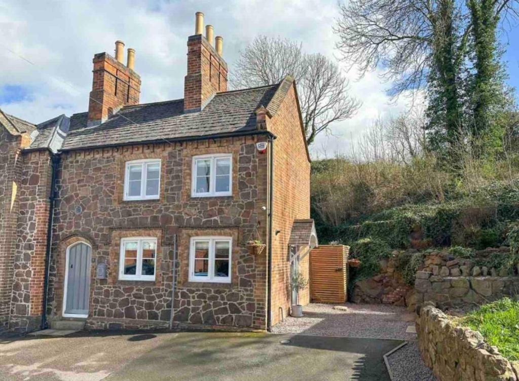 a brick house with white windows and a driveway at Honeysuckle Cottage in Mountsorrel