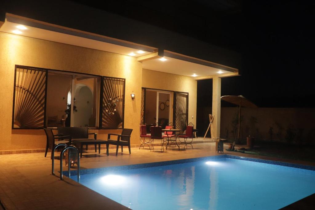 a swimming pool at night with chairs and a table at Peaceful Pool Villa in Marrakesh