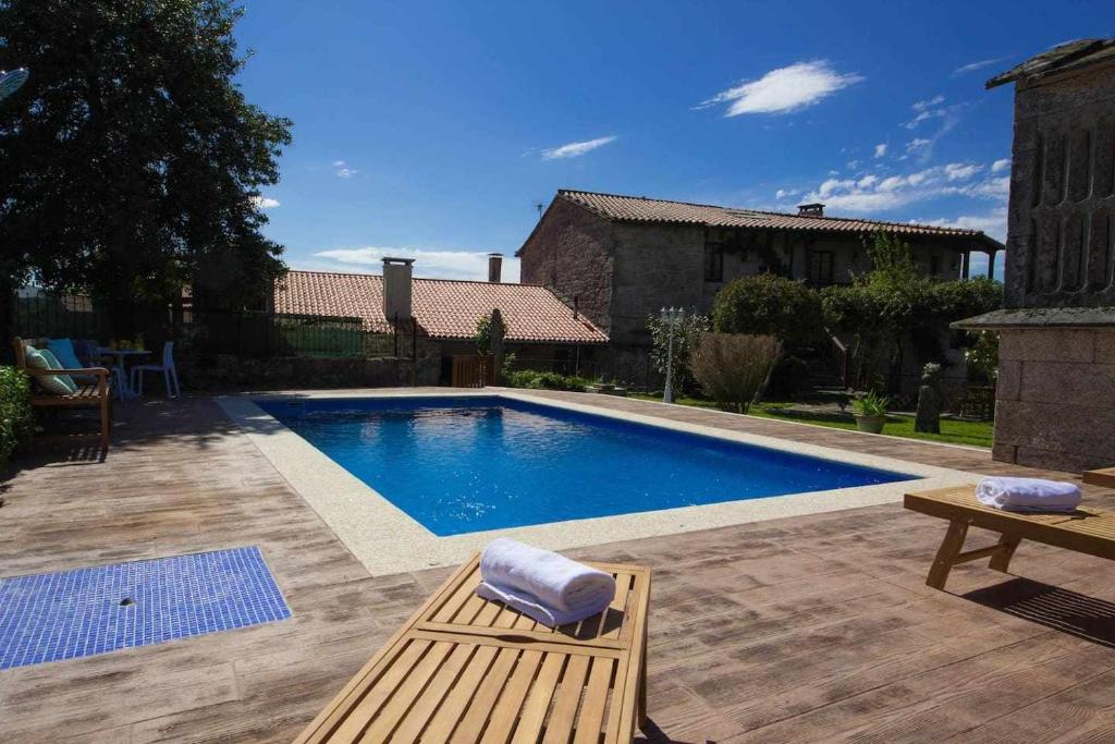 una piscina con un banco junto a una casa en Eira Grande Galicia Villas, en Pedre