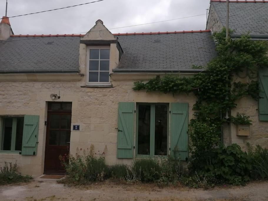 uma casa velha com persianas verdes e uma janela em Maison chaleureuse avec cheminée em Bourgueil