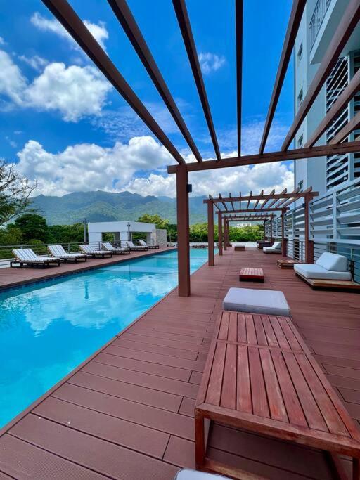 einen Pool mit Holzterrasse und Bänken neben einem Gebäude in der Unterkunft Merendon Heights Luxury Condo in San Pedro Sula