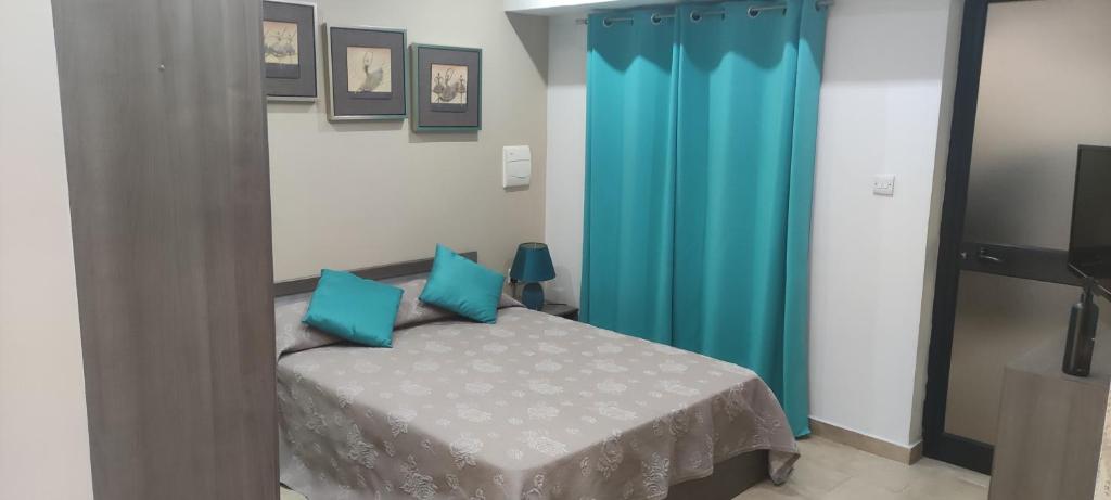 a bedroom with a bed with blue curtains at Home away from Home in Żurrieq