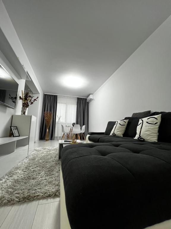 a bedroom with a black bed and a living room at New Residence Apartament in Popeşti-Leordeni