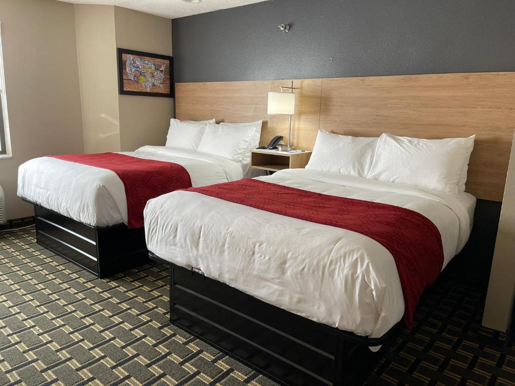 um quarto de hotel com duas camas com lençóis vermelhos em Edn Hotel em Peoria